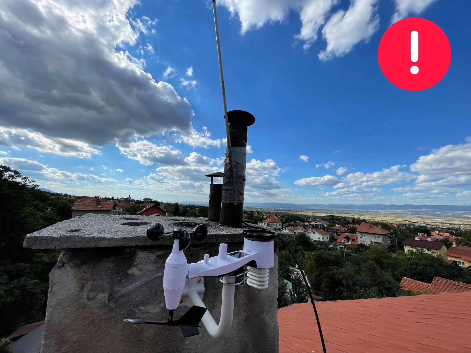 WeatherXM station mounted beside and below the top of a chimney structure